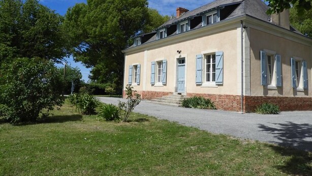 A two-story house with a brick base and a light-colored upper section, featuring blue shutters on the windows. - Charming Cottage Near Le Mans: Garden, Terrace, 4 Bedrooms, 3 Bathrooms, Wi-Fi, Family Friendly (Écommoy)