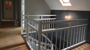 A room with a sloped ceiling, a skylight, a white railing, and a staircase. - Charming Cottage Near Le Mans: Garden, Terrace, 4 Bedrooms, 3 Bathrooms, Wi-Fi, Family Friendly (Écommoy)