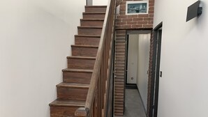 A wooden staircase with a brick wall and a door leading to a hallway. - Charming Beach House, Sleeps 10, 150m from Shore (Fort-Mahon-Plage)