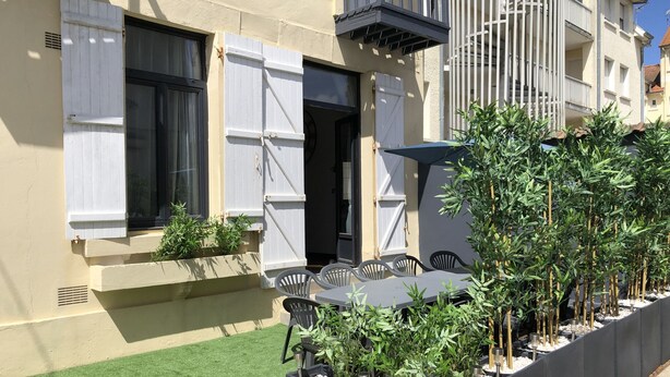 A building with a balcony, outdoor seating, and potted plants. - Charming Beach House, Sleeps 10, 150m from Shore (Fort-Mahon-Plage)