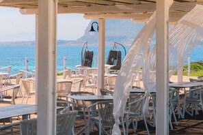 Relax under a pergola overlooking a serene body of water with a mountainous backdrop.