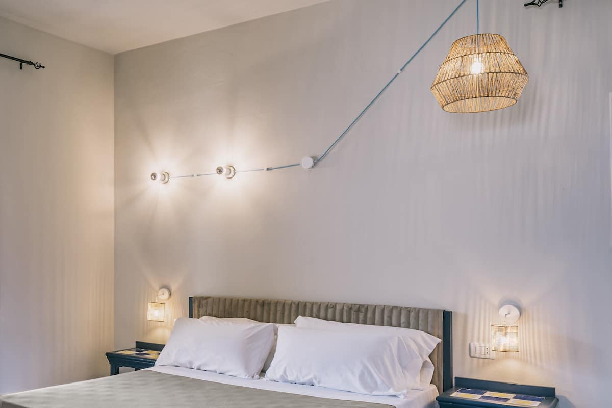 A modern bedroom with a large bed, two bedside tables, and a hanging light fixture.