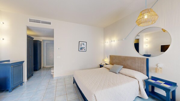 A modern bedroom with a large bed, a bedside table, a mirror, and a wardrobe. - Mangia's Favignana Resort (Favignana)