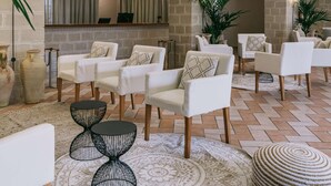 A spacious lobby with white armchairs, a patterned rug, and decorative wall art. - Mangia's Favignana Resort (Favignana)