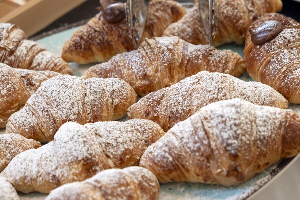 A display of assorted pastries, including croissants and chocolate-covered pastries, arranged on a tray.