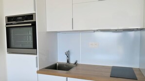 Eine moderne Küche mit weißen Schränken, einer Edelstahl-Spüle und einem eingebauten Backofen.