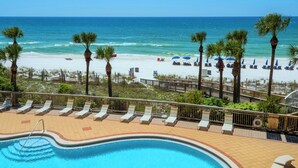 Ein Poolbereich mit Liegestühlen und Blick auf Strand und Meer.
