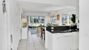 A modern kitchen with a black countertop, white cabinetry, and a large window providing a view of the outdoors. - 260B - Boca Retreat w/ Pool, Parking, Near Evert Tennis & Shops (Boca Raton)
