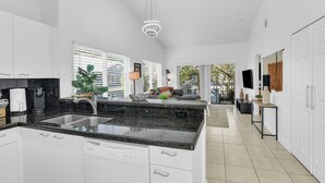 A modern kitchen with white cabinetry, a granite countertop, and a built-in dishwasher. - 260C - Apt in Boca Raton- Near Evert & Boca Prep (Boca Raton)