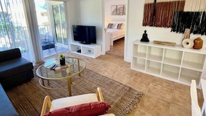 Un soggiorno moderno con televisore, divano e zona pranzo con tavolo in vetro.