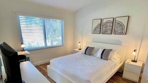 Una camera da letto con un letto, comodini, una scrivania e una finestra con persiane.