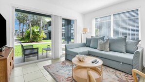 A modern living room with a grey sofa, a coffee table, and a TV. - 350B - Boca Retreat w/ Pool, Parking, Near Evert Tennis & Shops (Boca Raton)