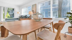 A modern dining area with a wooden table, cushioned chairs, and a decorative glass vase. - 350B - Boca Retreat w/ Pool, Parking, Near Evert Tennis & Shops (Boca Raton)