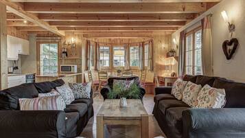 L’intérieur chaleureux d’un chalet avec des murs en bois, un coin repas et une cuisine équipée d’un four à micro-ondes.