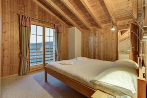A wooden room with a bed, a window with curtains, and a view of the outdoors. - Chalet Aurelia - La Tzoumaz, 4 Vallees (La Tzoumaz)