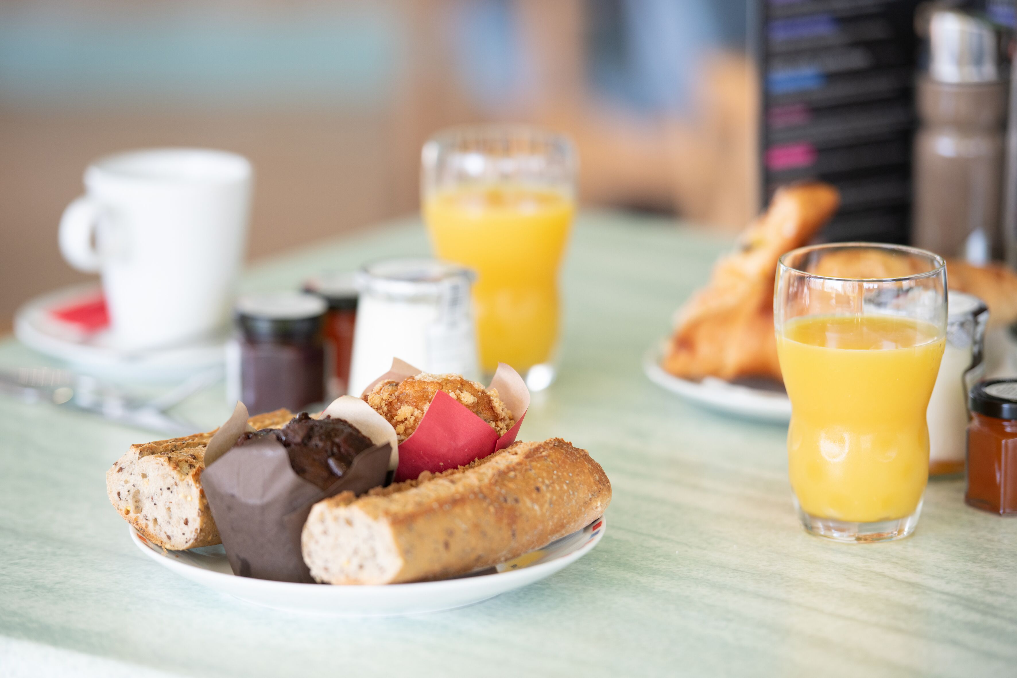 Una colazione con croissant, una tazza e bicchieri di succo d'arancia su un tavolo.