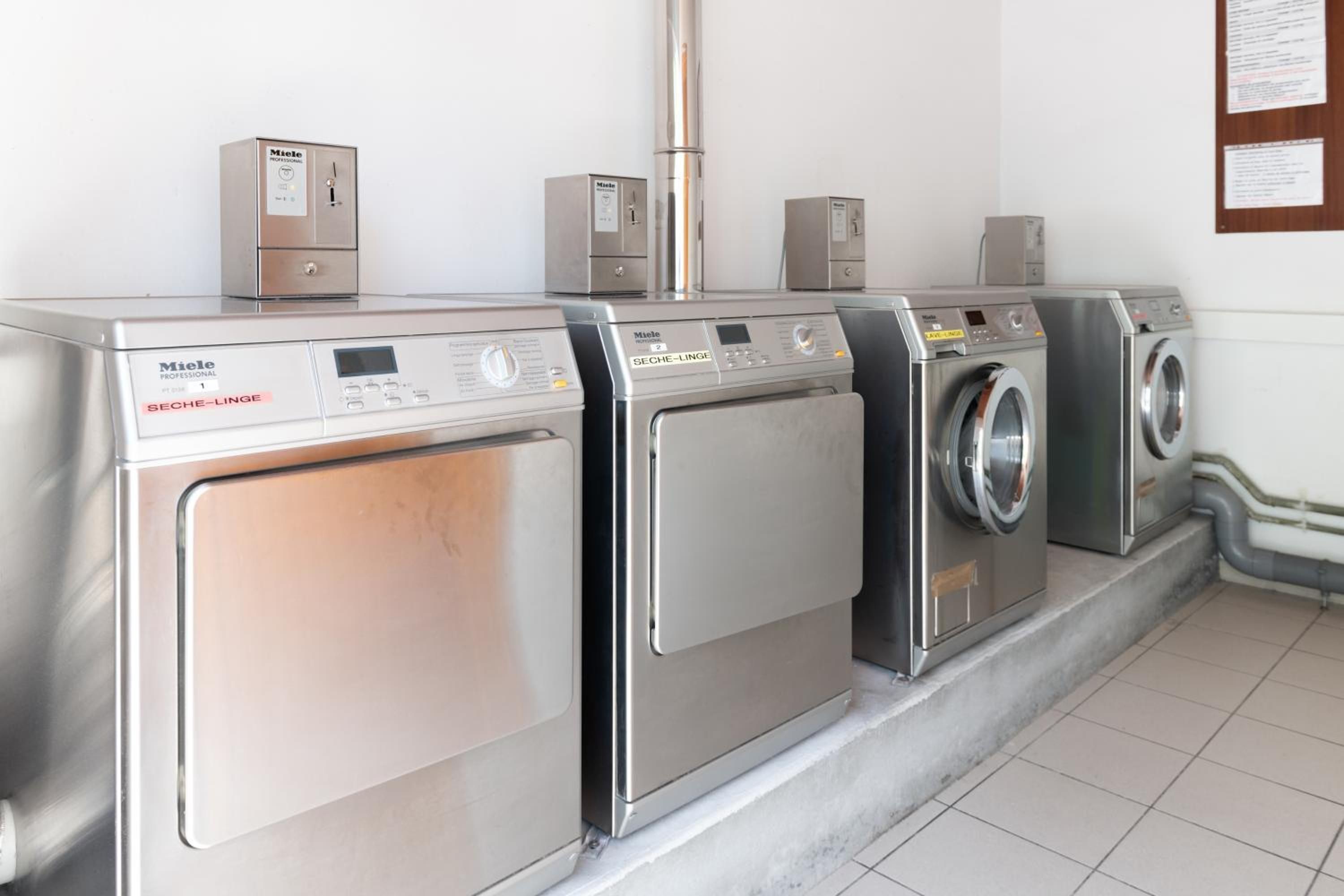 A row of professional-grade, stainless steel laundry machines in a clean, modern laundry facility.