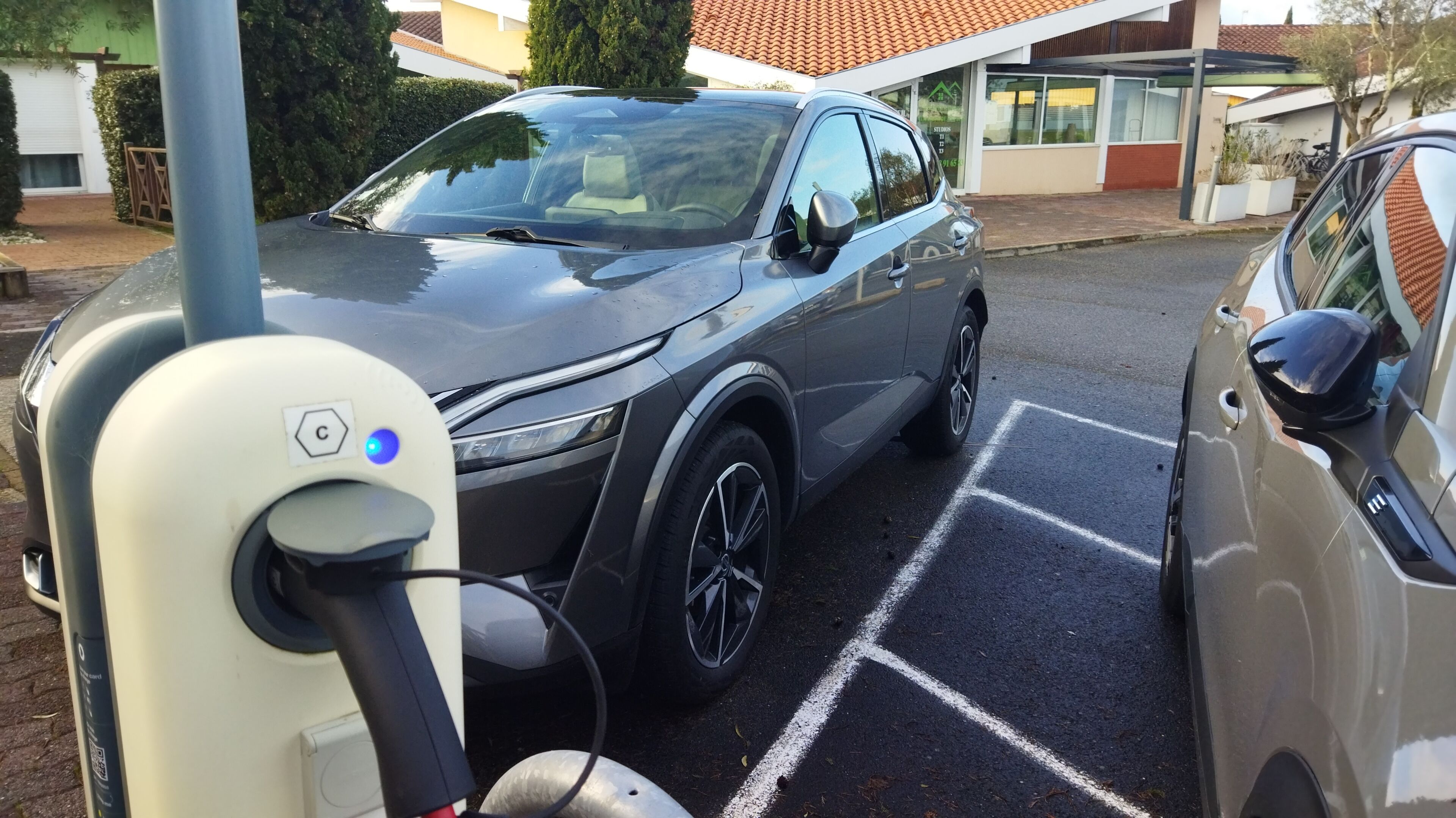 Parkeringsplads med ladestation og en parkeret bil.