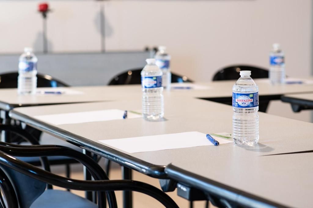 Un salón de conferencias con mesas, sillas y botellas de agua.