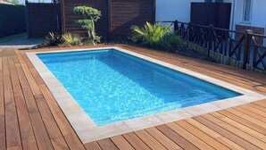 A rectangular swimming pool with a wooden deck surrounding it. - Résidence Amaréna (Saint-Paul-les-Dax)
