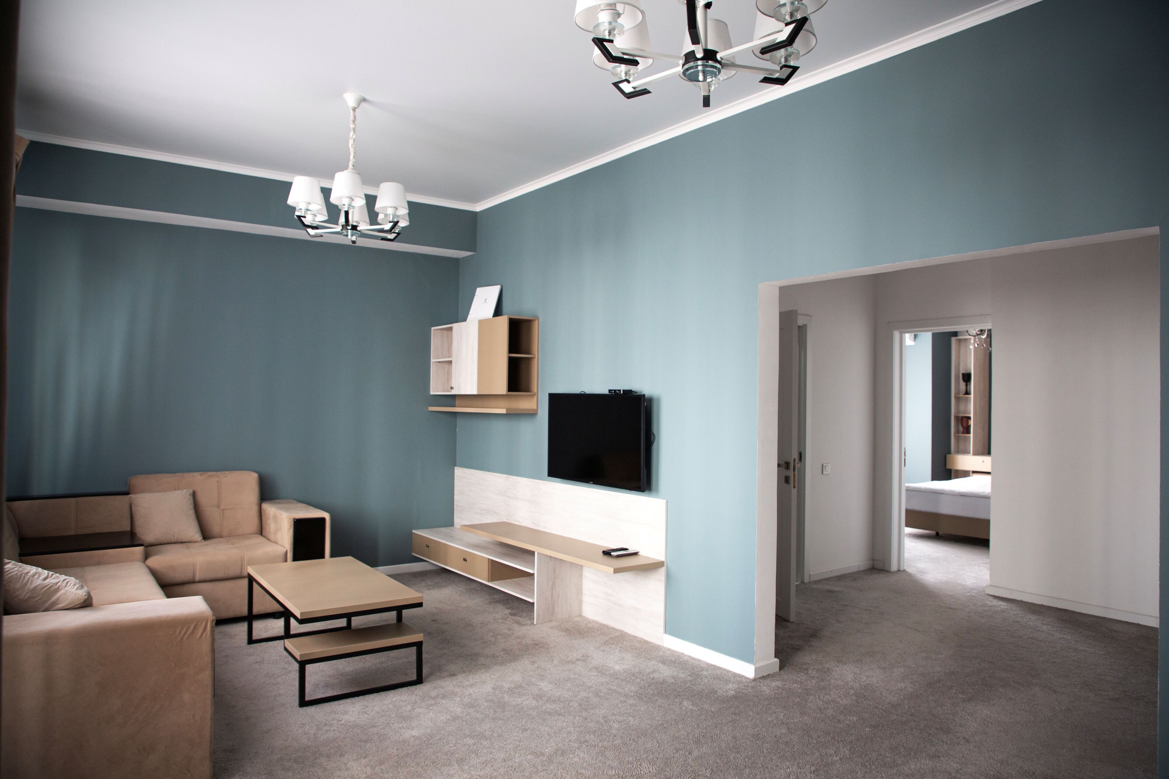 A modern living room with a sofa, coffee table, TV, and built-in shelving.