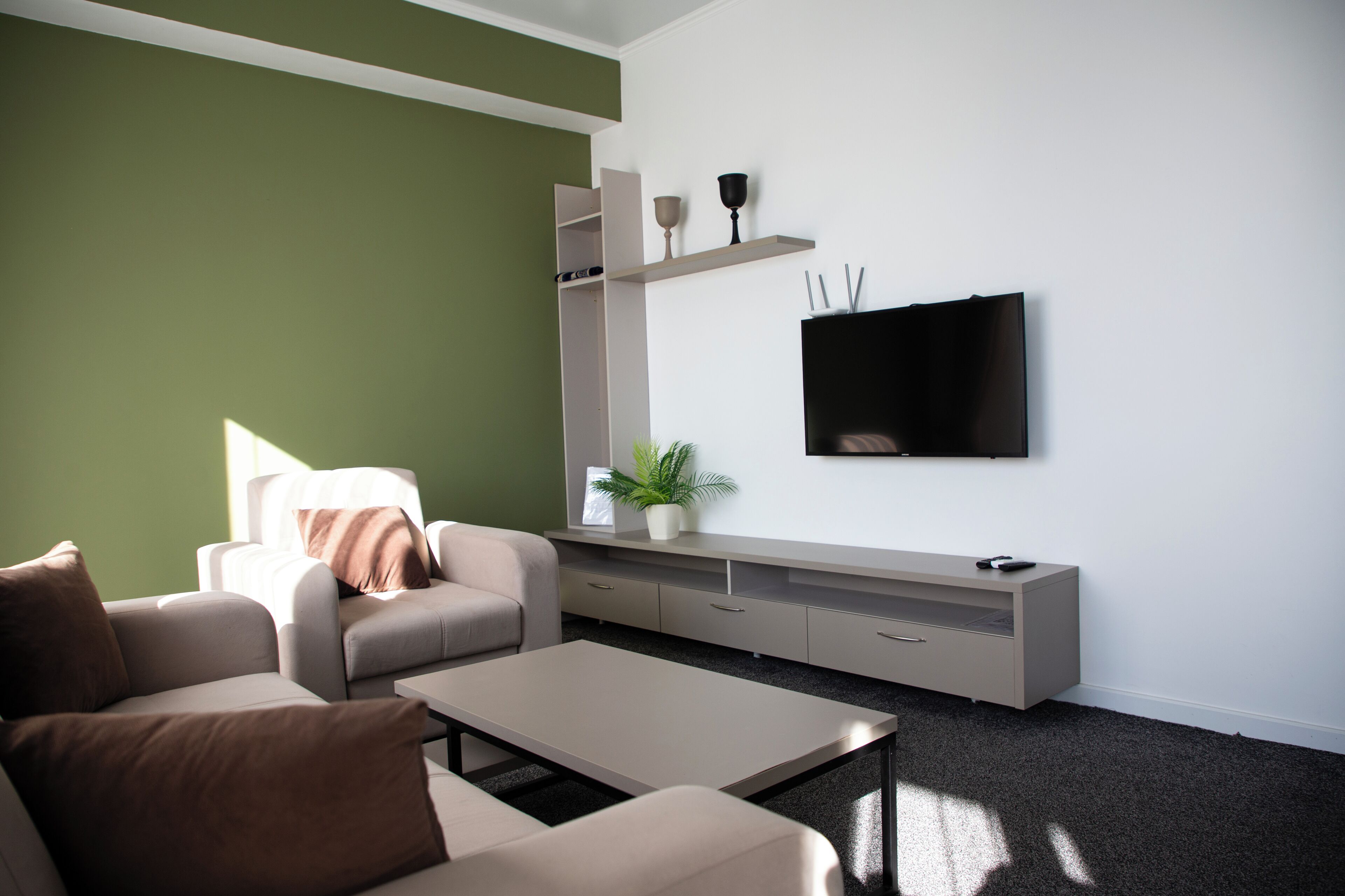 Ein modernes Wohnzimmer mit einer Couch, einem Couchtisch und einem an der Wand befestigten Fernseher.