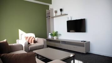 Ein modernes Wohnzimmer mit einer Couch, einem Couchtisch und einem an der Wand befestigten Fernseher.