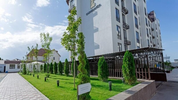 Un hotel moderno con un camino pavimentado, césped bien cuidado y un cartel que indica un lugar.