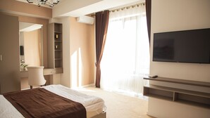 Una habitación de hotel con una cama, televisión, escritorio y una silla.