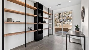 Ein modernes Interieur mit eingebauten Regalen, einem schwarzen Schrank und Blick durch Glastüren.