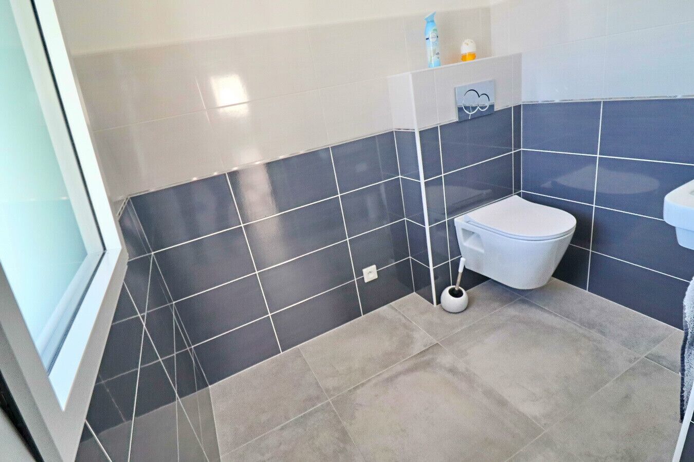 Ein Badezimmer mit Toilette, Bidet und Toilettenpapierhalterung.
