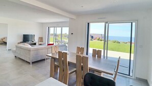 Ein modernes Wohnzimmer mit Sofa, Fernseher und Essbereich mit Stühlen.