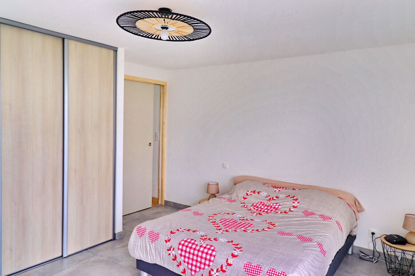 A bedroom with a bed, bedside lamps, a ceiling fan, and a wardrobe.