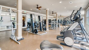 Une salle de sport équipée de tapis de course, d’appareils de musculation et de poids libres.
