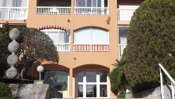 A multi-story building with a central entrance, balconies, and a stone staircase leading up to the entrance. - Studio rental (Saint-Mandrier-sur-Mer)