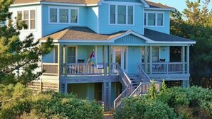 A two-story house with a covered porch and a staircase leading to the upper level. - CheckMate: Walk to Beach, Large Pool, Hot Tub (Southern Shores)