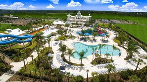Ein Resort mit großem Pool, Wasserrutschen und einem Golfplatz im Hintergrund.