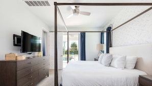A bedroom with a four-poster bed, a television on a dresser, and a view of the outdoors. - Entertaining Retreat with Themed Bedrooms at Encore (Kissimmee)
