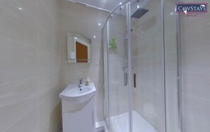 Een moderne badkamer met een douchecabine van glas, een wit wastafelmeubel en een spiegel erboven.