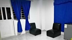 Ein Zimmer mit zwei schwarzen Ledersesseln, einem weißen Heizkörper und blauen Vorhängen.