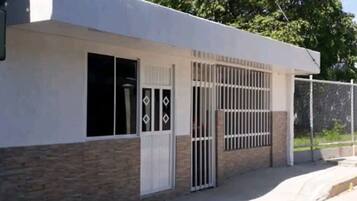 A building with a white exterior, a gated entrance, and a window with a diamond-shaped design.