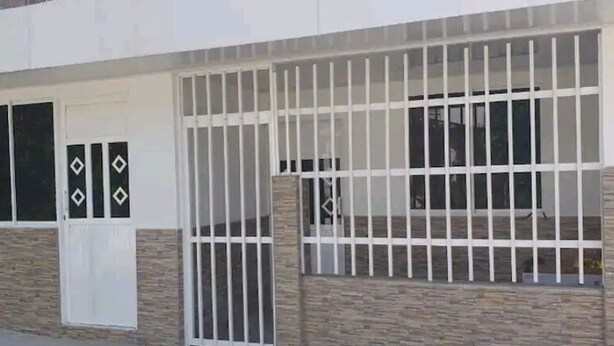 Ein Gebäude mit einem vergitterten Eingang, einer Tür mit Fenster und einem Fenster mit Gittern.