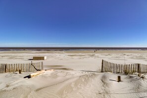 A sandy beach with a wooden fence and a concrete structure.