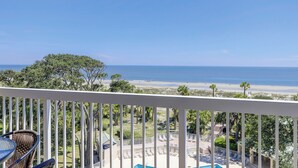 A balcony with a view of a beach and ocean.