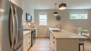 Una cocina moderna con electrodomésticos de acero inoxidable, una isla central e iluminación colgante.