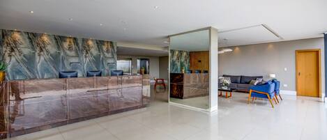 A spacious lobby with a marble reception desk, a sofa, and a wooden door.
