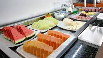 Buffet com diversas frutas e queijos.