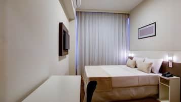 Ein Hotelzimmer mit Bett, Nachttisch, Stuhl und Schreibtisch.
