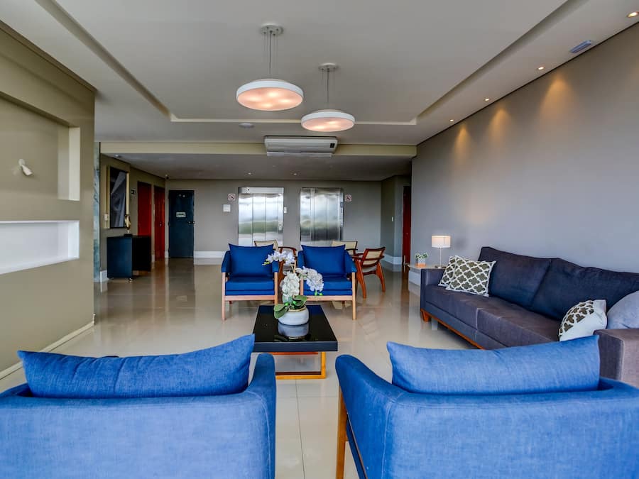 Una sala de estar moderna con sofás azules, una mesa de centro y una zona de comedor con una silla roja.