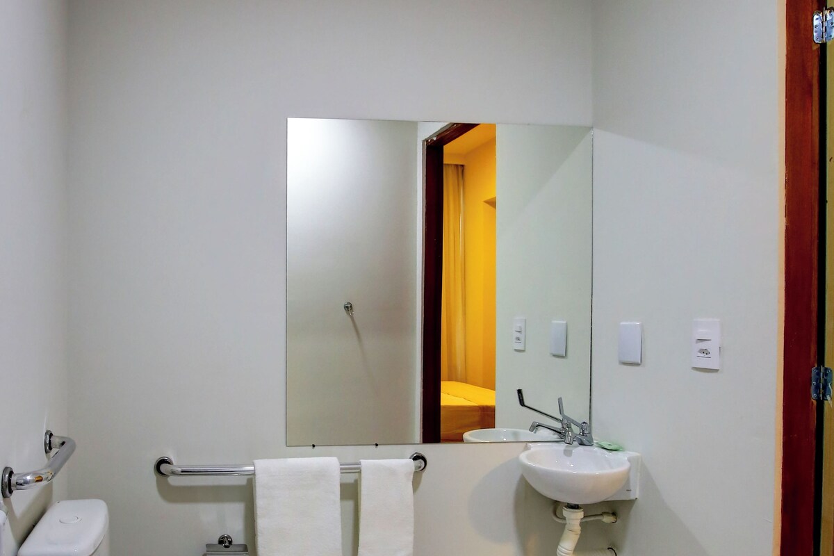 A bathroom with a toilet, sink, mirror, and shower.